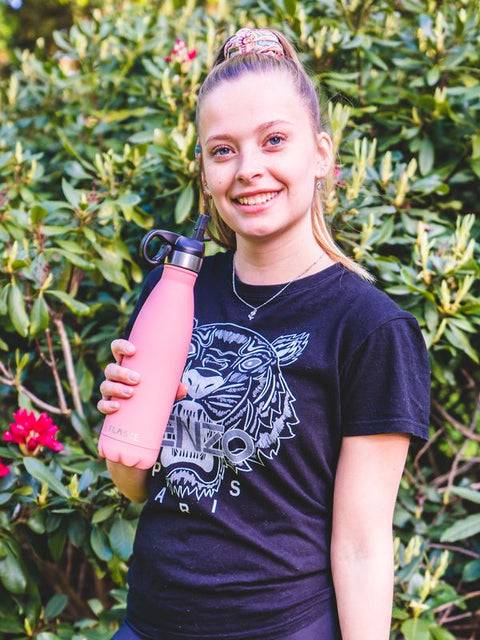 Woman smiling with a pink FLASKE bottle