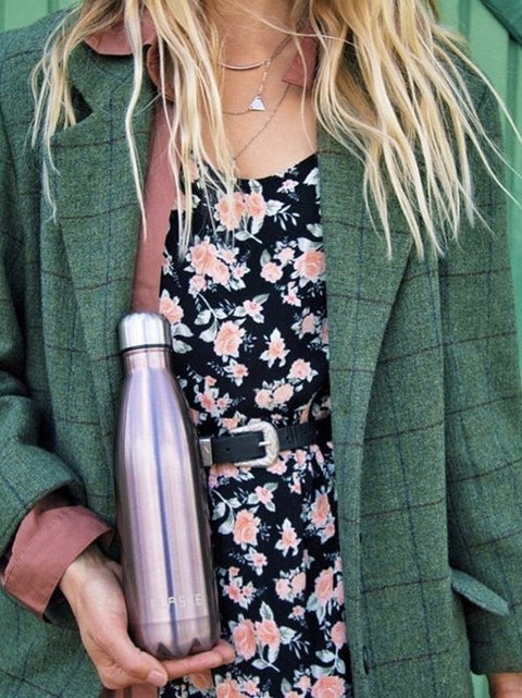 Woman in a green coat holding a FLASKE bottle