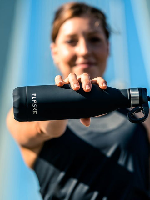 Woman holding her FLASKE bottle out to the camera