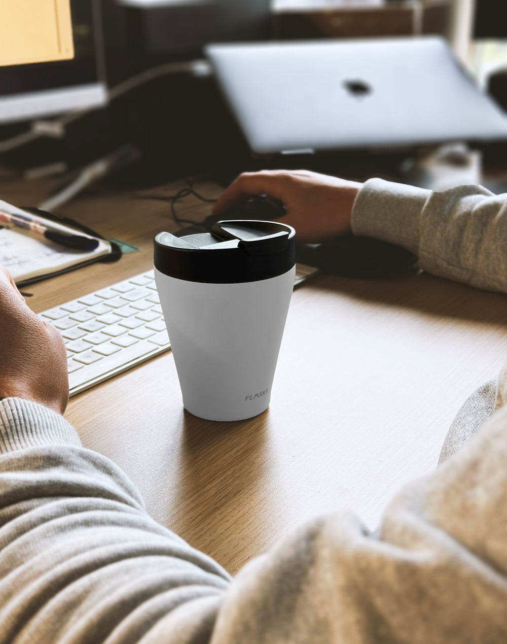 White FLASKE EVO Coffee Cup on a desk next to a laptop