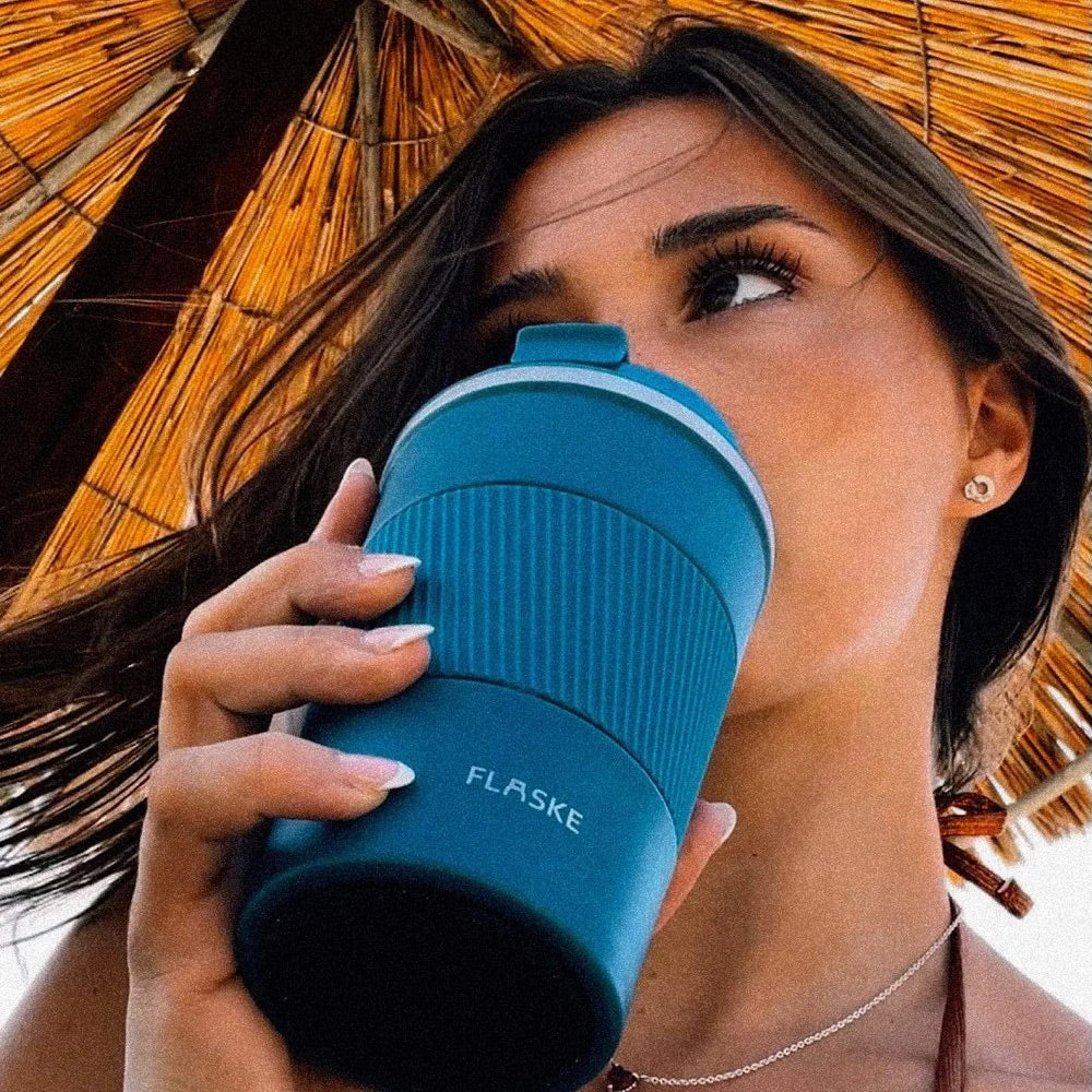 Woman drinking from the FLASKE Coffee Cup 380ml in Water at the beach
