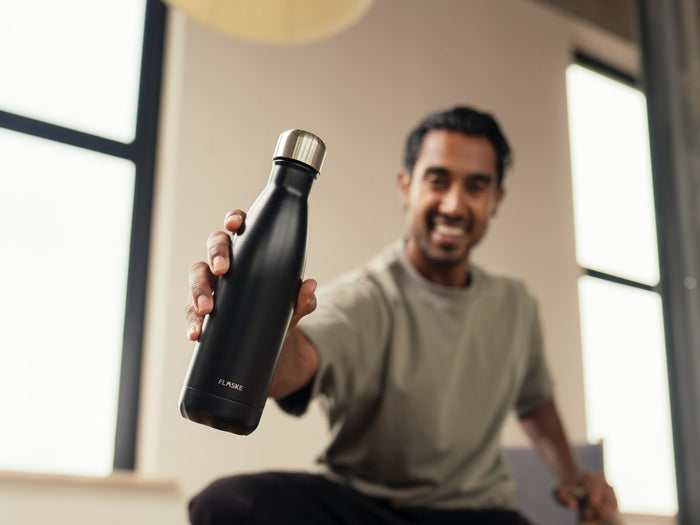 Man showing his black FLASKE bottle to the camera